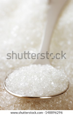 Close-up of granulated sugar in spoon and sugar pile.