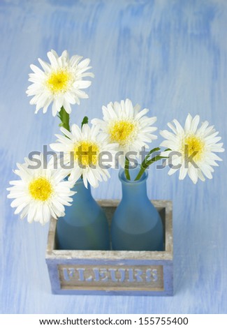 Daisy bouquet in vase on grunge background.