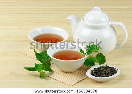 Two tea bowls and teapot on bamboo mat.