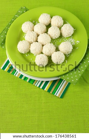 Coconut candies in plate on green cloth.