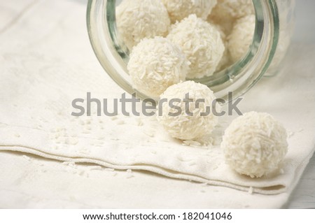 Close-up of coconut candies spilled of glass jar.