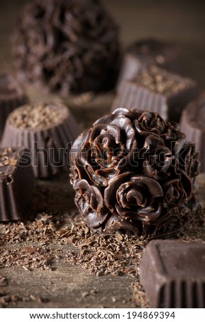 Homemade natural chocolate candies with chips on wooden background.