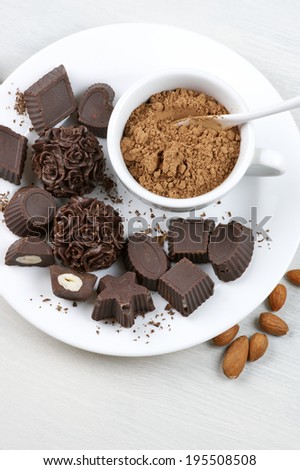 Homemade natural chocolate candies with ingredients on white plate.