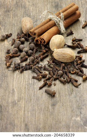 Cinnamon, nutmeg, allspice and cloves on wooden background. Top view point.