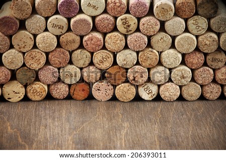 Stack of assorted wine corks on wooden background.