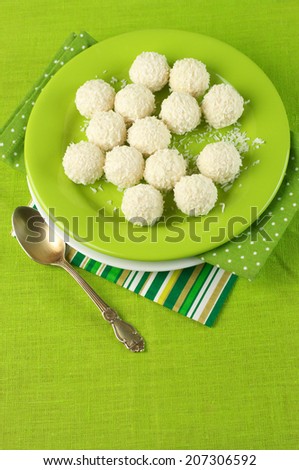 Coconut candies in plate on green cloth.