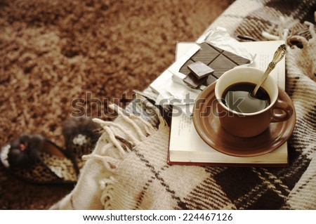 Woolen plaid, coffee cup, book and slippers on shaggy carpet. Top view.