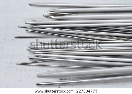 Set of vintage gray metallic knitting needles on rustic wooden table. Top view point.