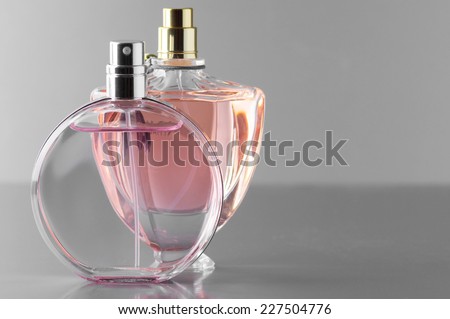 Two various bottles of woman perfume on gray background.