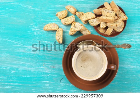 Cup of coffee latte and almond cookies on aquamarine wooden background. Top view point. Focus on coffee.