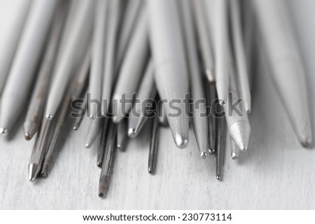 Set of vintage gray metallic knitting needles on rustic wooden table close-up. Shallow DOF.