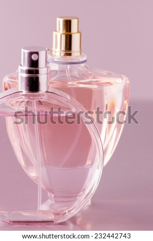 Two various bottles of woman perfume on pink background. Toned image.
