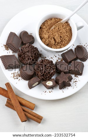 Homemade natural chocolate candies with ingredients on white plate.