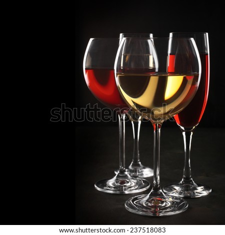 Various glasses of red and white wine with abstract pattern on black background.