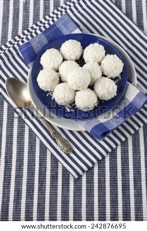Coconut candies in plate on striped cloth.
