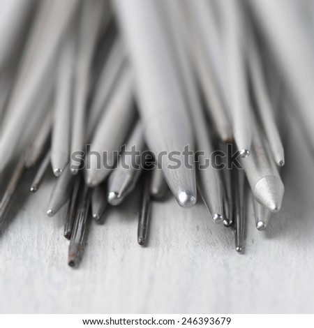 Set of vintage gray metallic knitting needles on rustic wooden table close-up. Shallow DOF.