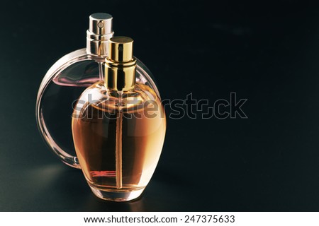 Two bottles of woman perfume on dark background with copy space.