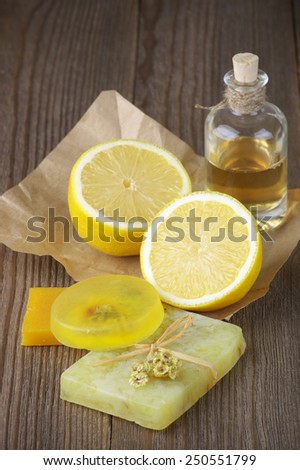 Various natural soaps, lemon and bottle of oil on rustic wooden background.