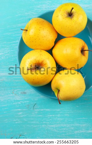 Yellow Golden Delicious apples in plate on turquoise rustic wooden table. Top view point.