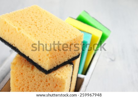Cleaning sponges in rustic box on wooden background.