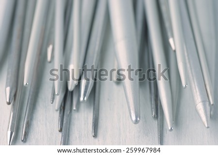 Set of vintage gray metallic knitting needles on rustic wooden table close-up. Toned image. Shallow DOF.