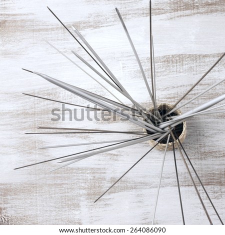 Bunch of knitting needles in basket on rustic wooden table. Top view point. Shallow DOF.