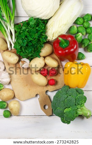 Assorted vegetables and cutting board on white wooden background. Top view point.