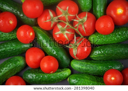 Heap of whole wet tomatoes and cucumbers. Top view point, full frame.