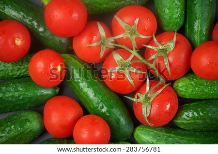 Heap of whole wet tomatoes and cucumbers. Top view point, full frame.