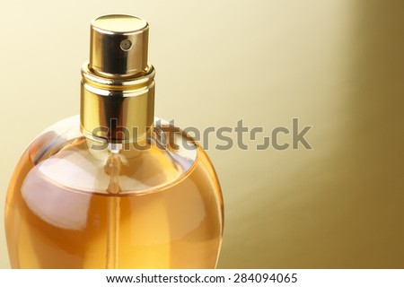Bottle of woman perfume close-up on gold background.