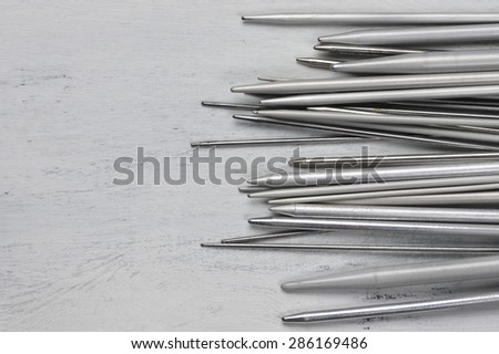 Set of vintage gray metallic knitting needles on rustic wooden table. Top view point.