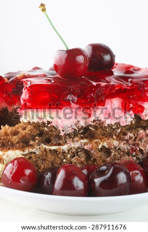 Fruity cake with jelly and cherries close-up in white plate on white background.