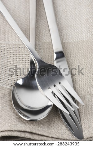 Cutlery set: spoon, fork and knife on linen napkin close-up.