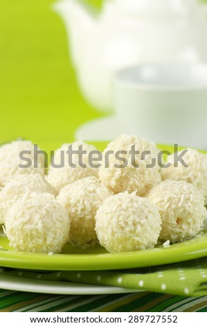 Coconut candies and tea on green cloth.