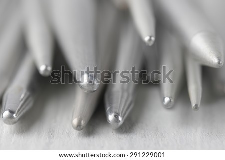 Extreme close-up of vintage gray metallic knitting needles on rustic wooden table. Shallow DOF.