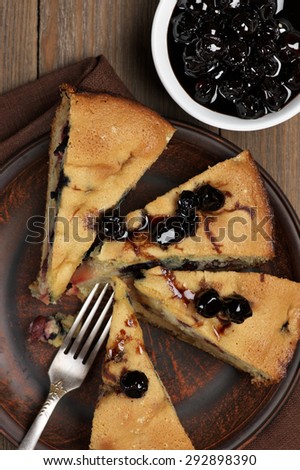 Slices of fruit pie with berries in brown plate on wooden table. Top view point.