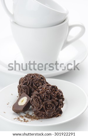 Homemade natural chocolate candies and cups on white background.