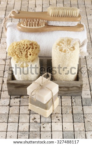 Set of bathroom accessory on stone tile: soaps stack, loofah, sponge, brushes, towel.