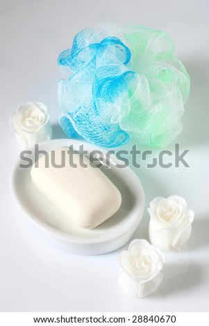 Blue&green sponge, bar of soap and soap roses on light background.
