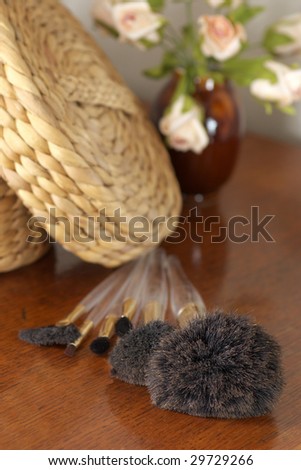 Wicker casket, make-up brushes and roses on wood dressing table. Selective focus (large brushes).