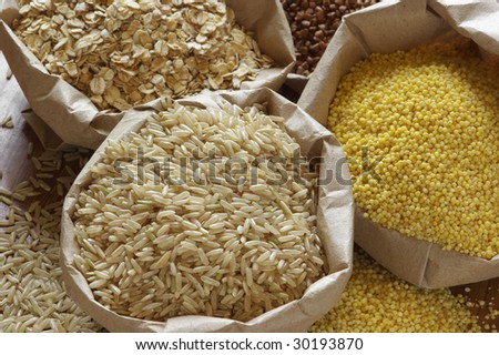 Brown rice, oatmeal, millet and buckwheat in paper bags.