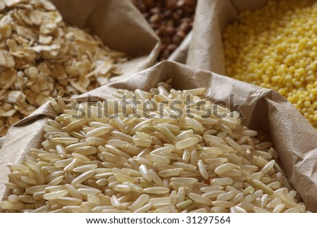 Brown rice, oatmeal, millet and buckwheat in paper bags close-up.