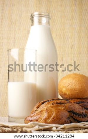 Two buns, bottle of milk and glass of milk on wicker background.