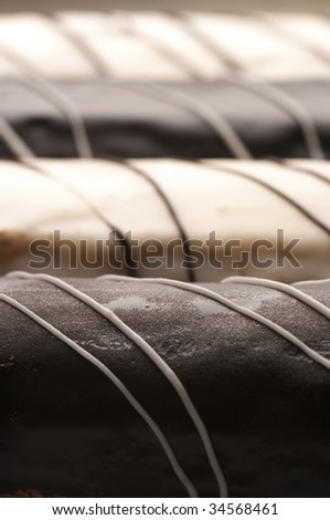 Four sponge cakes of white and dark chocolate close-up in row. Selective focus on front cake.