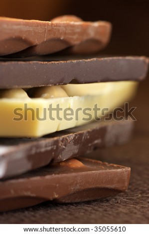 Stack of various chocolate close-up on brown canvas. Shallow DOF.