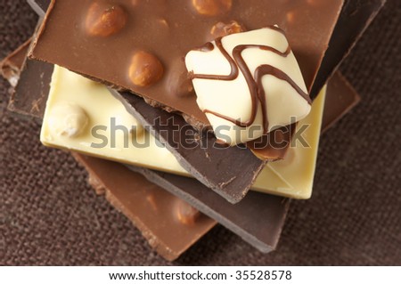 Stack of various chocolate and candy on brown canvas. Shallow DOF.
