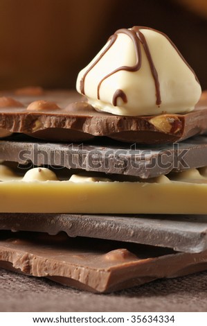 Stack of various chocolate and candy close-up on brown canvas. Shallow DOF.