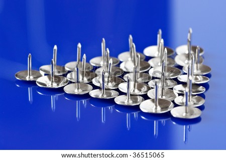 Group of metal pushpins close-up on blue background.