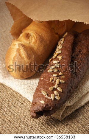 Rye and wheat bread in paper bag on sack.