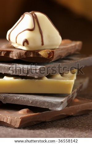 Stack of various chocolate and candy close-up on brown canvas. Shallow DOF.